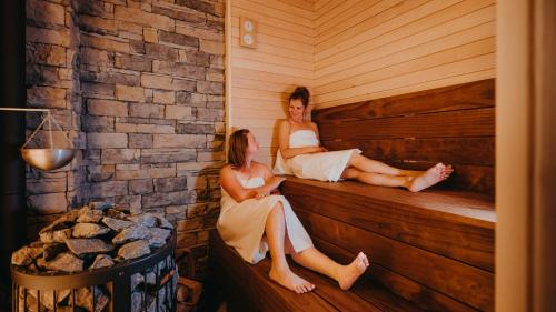 two women sitting on the side of a sauna at Vila Roháčka - Luxusná Vila so súkromným wellness a bazénom in Habovka