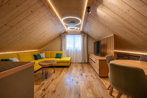 a living room with a yellow couch and a table at Vila Roháčka - Luxusná Vila so súkromným wellness a bazénom in Habovka