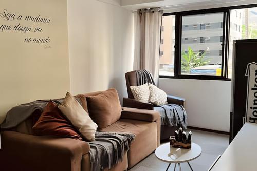 a living room with a couch and a window at Lindo Flat a poucos passos da praia in Maceió