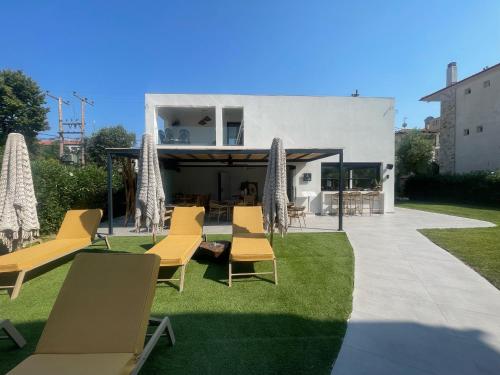 a patio with chairs and umbrellas on the grass at Olvion Luxury Living in Kallithea Halkidikis
