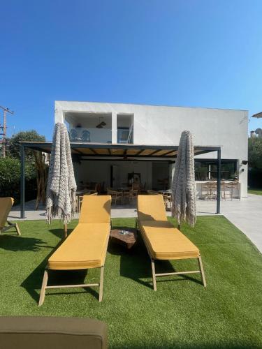 two chairs and a table on grass with a building at Olvion Luxury Living in Kallithea Halkidikis