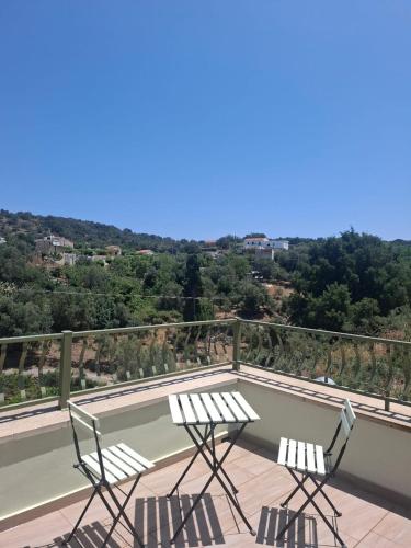 two chairs and a table on a balcony with a tennis court at Villa Quercus in Alikampos