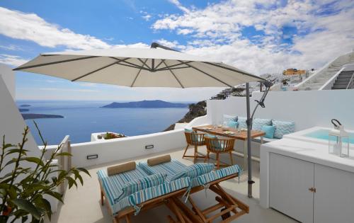 a balcony with an umbrella and a table and chairs at Olea Cave House in Imerovigli