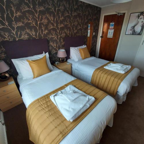 a hotel room with two beds with towels on them at The Kenbury B&B in Shanklin
