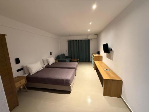 een slaapkamer met een bed, een bureau en een televisie bij Skiathos Bliss Villa in Skiathos-stad
