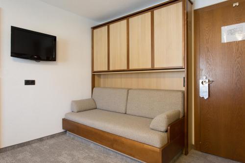 a room with a couch and a tv and a door at Ferienhotel Bergland in Arzl im Pitztal