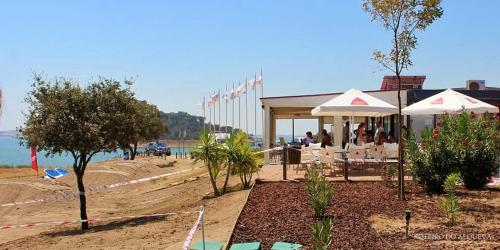 a group of people sitting under umbrellas on a beach at Campinho Guest house in Campinho