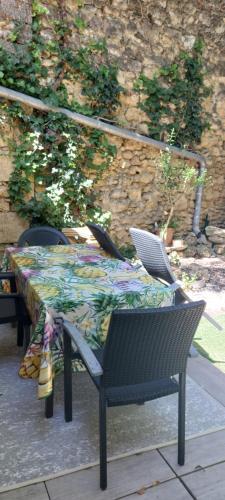 a table and chairs with a floral table cloth on it at Maison vieilles pierres proche plages in Fabrègues