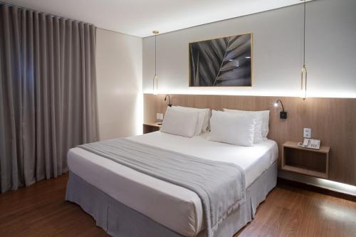 a hotel room with a large bed with white sheets at Jk Premium Hotel e Eventos in Londrina
