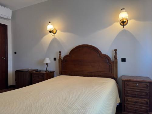 a bedroom with a bed and two lights on the wall at Residencial Deu-La-Deu by Hotel Dom Afonso in Monção