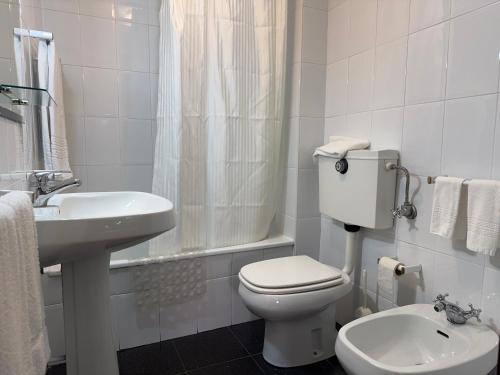 a white bathroom with a toilet and a sink at Residencial Deu-La-Deu by Hotel Dom Afonso in Monção