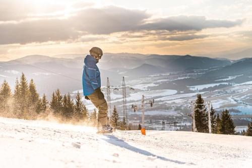 a man riding a snowboard down a snow covered slope at Wellness Chata Chmaroška - Telgárt Resort in Telgárt