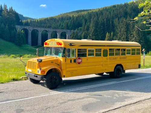 a yellow school bus driving down a road at Wellness Chata Chmaroška - Telgárt Resort in Telgárt