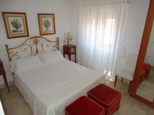 1 dormitorio con cama blanca y taburete rojo en Silenzi Holiday Home en Fertilia