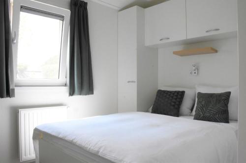 a bedroom with a white bed and a window at Recreatie aan de Vecht, chalet 3, genieten van de rust en ruimte en toch dichtbij de stad in Weesp