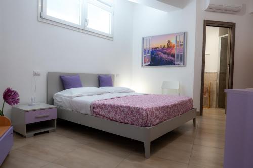 a bedroom with a bed with purple sheets and a window at La dimora dei ricci in Santo Stefano di Camastra