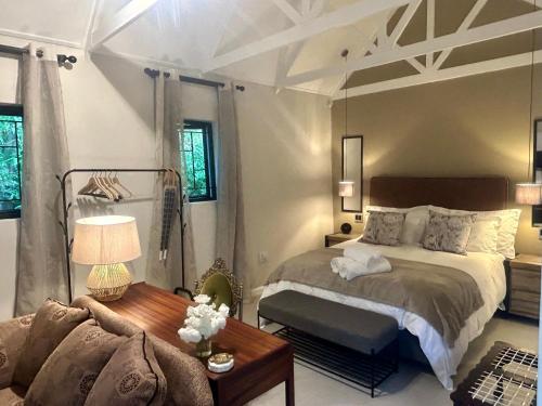 a bedroom with a bed and a table and a couch at Rosebud Cottages in George