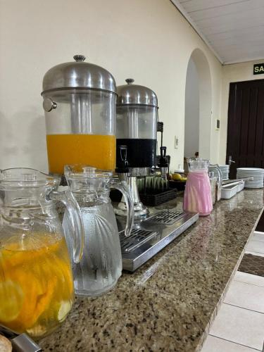 a kitchen counter with a juicer and pitchers of orange juice at Hotel Comodoro De Livramento in Santana do Livramento
