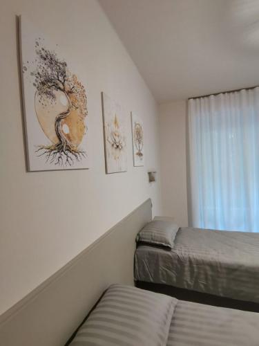 a bedroom with two beds and paintings on the wall at Angela's House in Alessandria