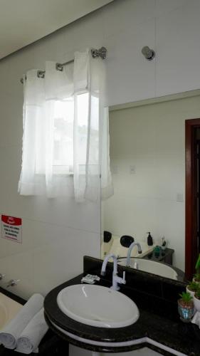 a bathroom with a sink and a mirror at Hotel Yoguedes in Padre Paraíso