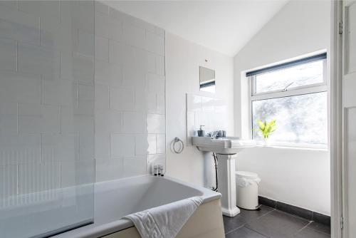 un bagno bianco con vasca e lavandino di Spacious 5BR House in Central Derby - Near Amenities a Derby