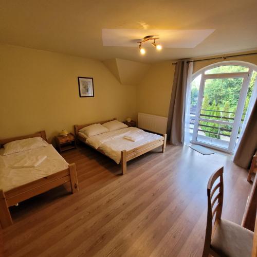 a bedroom with two beds and a large window at Willa Roztocze in Zwierzyniec