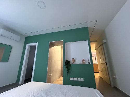 マルサシュロックにあるStylish Seaside 1br Maisonette Marsaxlokk Bayの緑の壁と白いベッドが備わるベッドルーム1室
