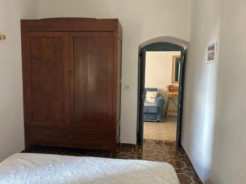 a bedroom with a large wooden cabinet next to a door at Casa del Gelsomino in Cuglieri
