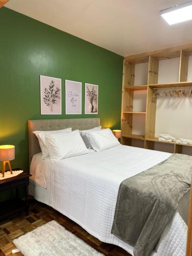 a bedroom with a large bed with a green wall at Frank Haus Hospedaria in Treze Tílias