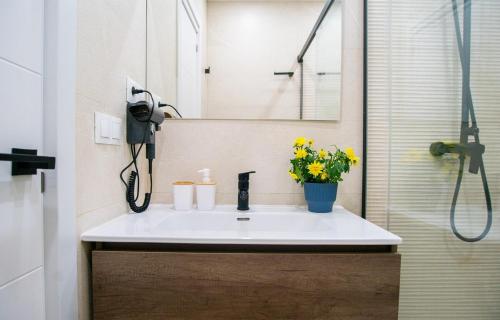 ein Badezimmer mit einem Waschbecken, einem Spiegel und Blumen in der Unterkunft Exclusive Luxury Comfort Stay - Malaga Center in Málaga