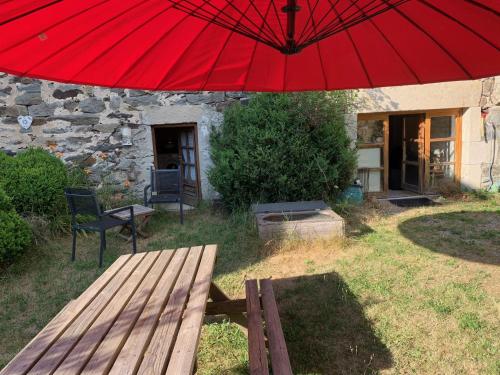 a red umbrella over a wooden bench in a yard at Domaine Au Vert Gna ! in Saint-Hostien