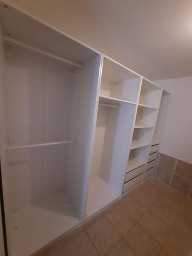 a white walk in closet with white shelves at Location maison de bourg in Poncin