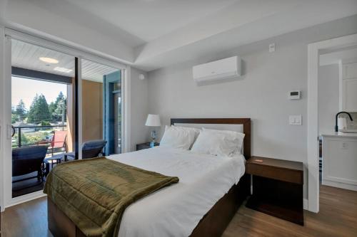 a bedroom with a large bed and a balcony at Harrison Hot Springs Lakeside in Harrison Hot Springs