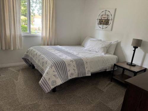 a bed in a white room with a window at Blue Cypress in Tofino