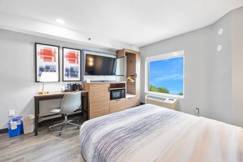 a bedroom with a bed and a desk and a tv at AmericInn by Wyndham Urbana Champaign University Area in Champaign