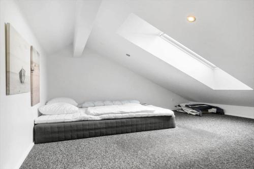 a white bedroom with a bed in a attic at 1130-Ringkobing-Sletten-18 in Ringkøbing