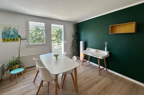 a dining room with a white table and a green wall at Escapade aux portes de Bordeaux, confort et nature in Villenave-dʼOrnon