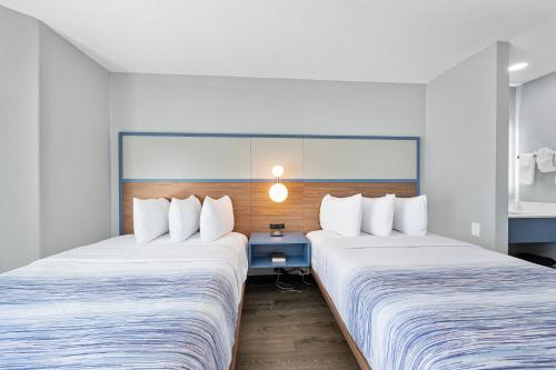 a hotel room with two beds and a blue table at AmericInn by Wyndham Urbana Champaign University Area in Champaign