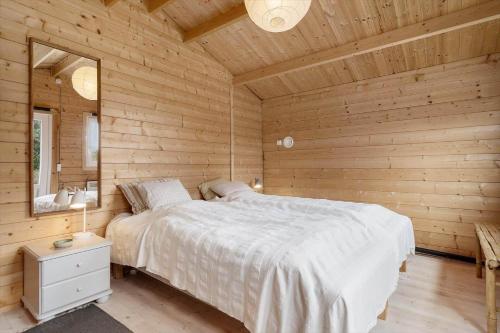 una camera da letto con un letto in una cabina di legno di 1083-Ringkobing-Spaettedalen-6 a Nørby