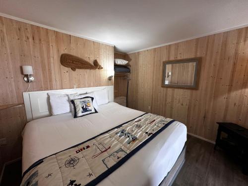 a bedroom with a large bed with wooden walls at Tillicum Beach Motel - Formerly Deane's Oceanfront Lodge in Yachats