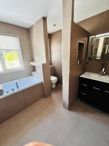 a bathroom with a tub and a toilet and a sink at Creek view house in Feock