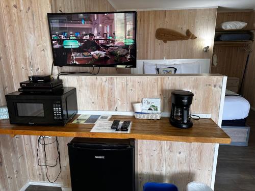 a room with a desk with a microwave and a tv at Tillicum Beach Motel - Formerly Deane's Oceanfront Lodge in Yachats