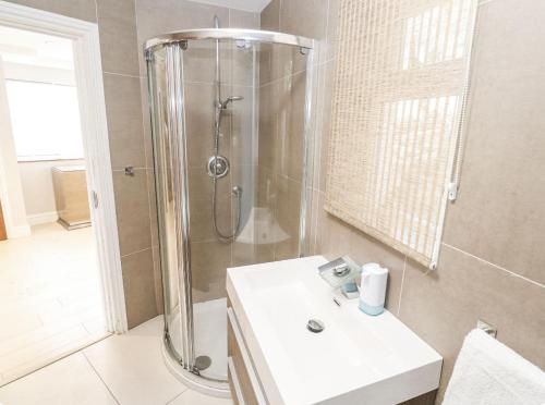 a bathroom with a shower and a white sink at Creek view house in Feock