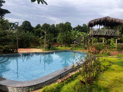 a large swimming pool in a yard with a playground at Khet - A Rural Farmstay in Jagdalpur