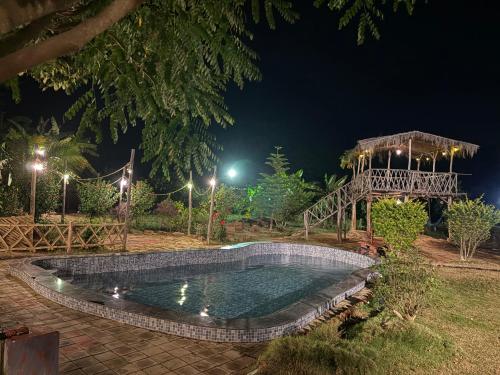 a swimming pool at night with a gazebo at Khet - A Rural Farmstay in Jagdalpur