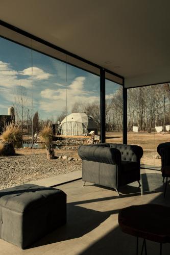 a living room with a couch and a large window at Los Cardos Lodge & Glamping in Malargüe