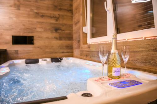 a hot tub with a bottle of champagne and two wine glasses at Apartmani Petra i Tea in Krapina