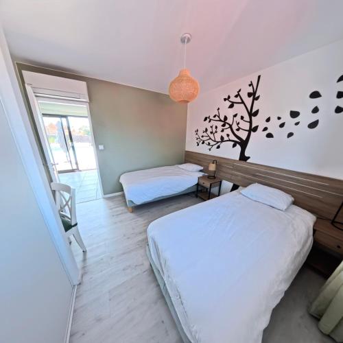 - une chambre avec un lit et un arbre sur le mur dans l'établissement Villa Chrisaline, spacieuse et climatisée, 5 chambres, piscine privée, à Moliets-et-Maa