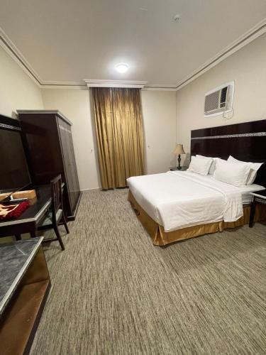 a hotel room with a large bed and a desk at Lamasat Al Ajnaha Serviced Apartments in Abha