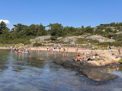 a group of people on a beach near the water at Backstugan - litet hus med storslaget läge in Västra Frölunda